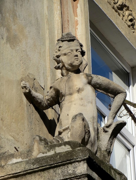 Stone figure statue boy on the balcony by the window of the old building