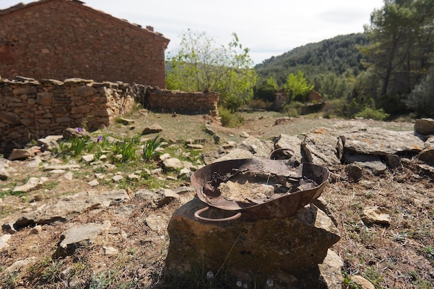 A stone fire pit in front of a house with a mountain in the background.