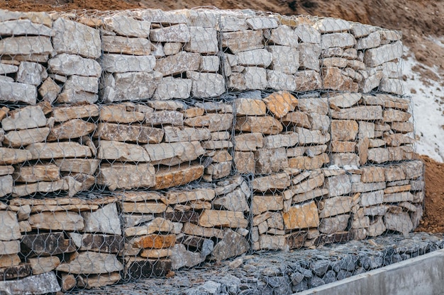 Stone gabion wall along the asphalt road in winter