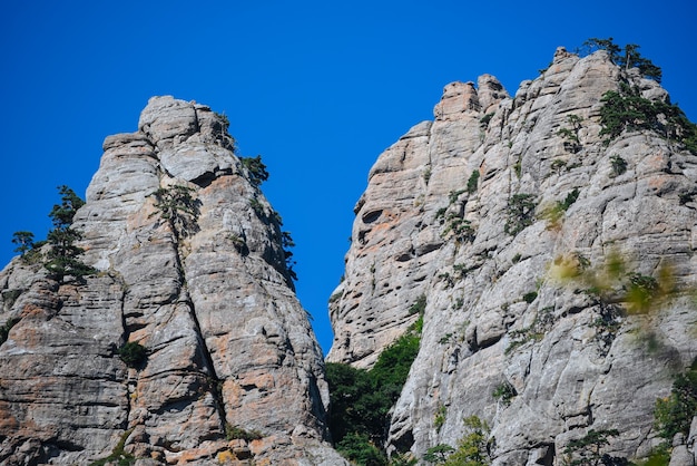 Stone hills and mountains with green trees and bushes against the blue sky