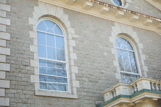 A stone house with a large window and a balcony.