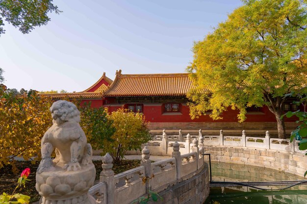 A stone lion statue stands in front of a building with a red roof.