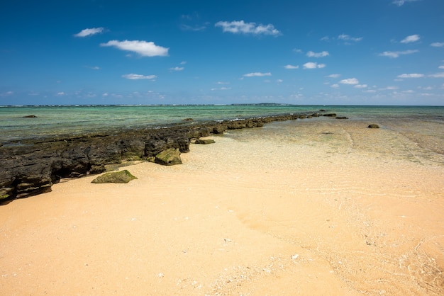 Stone platform  in diagonal separates sea from the golden sand on a beautiful sunny day Iriomote Island