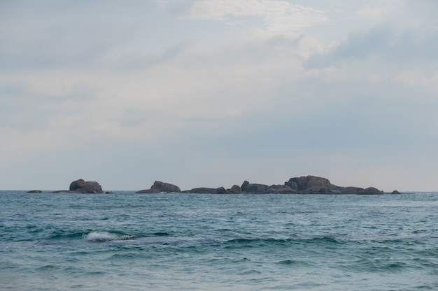 A stone ridge in the ocean, among the waves.