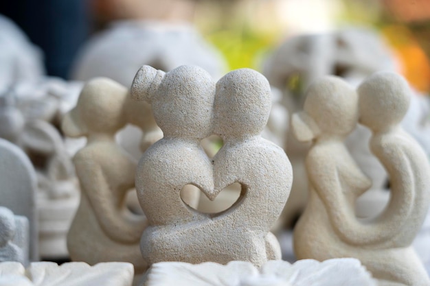 Stone statuette of a couple in love with a heart inside Souvenir on display for sale on street market in Ubud Bali Indonesia