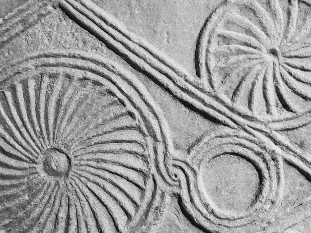 Stone texture circles are carved on a heavy sandy board rock drawing ancient art of tribes