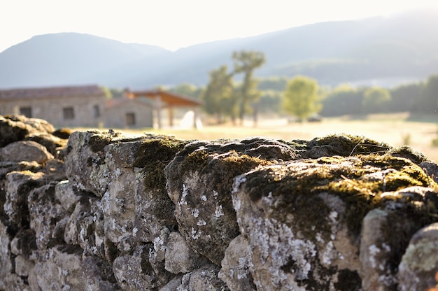 Stone wall with moss and unfocused cottage