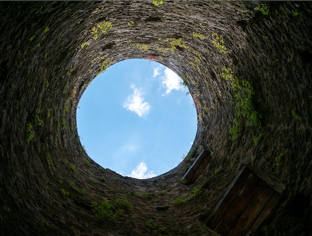 Photo stone well hole old construction from inside brick walls and blue sky background fall down in the well concept