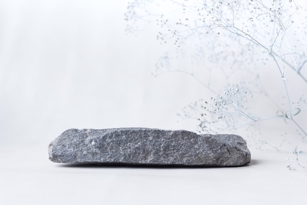 Stone with flowers on a light background. Catwalk for the presentation of products and cosmetics.