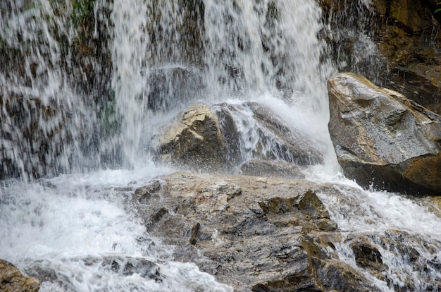 A stone with a flowing waterfall in the background