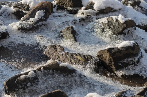 Stones covered with ice and snow closeup Texture of stones in the snow Marine stones covered by an ice