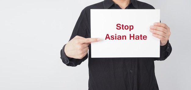 Stop asian hate in red color write in white board paper.Asian man wear black shirt holding paper on white background.