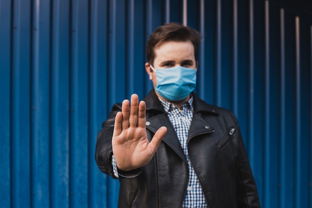 Stop coronavirus. man showing gesture stop. man wears protective mask against infectious diseases and flu. health care concept. coronavirus quarantine.