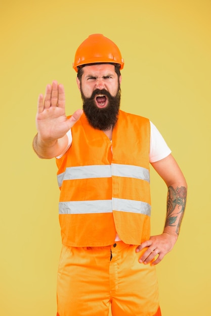 Stop mining area under construction Mining engineer showing caution sign on yellow background Construction worker or man miner warning about mining activities Mining and metallurgical industry