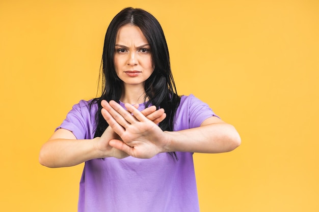 Stop or no sign Young beautiful hispanic sad woman serious and concerned looking worried and thoughtful facial expression feeling depressed isolated over yellow background