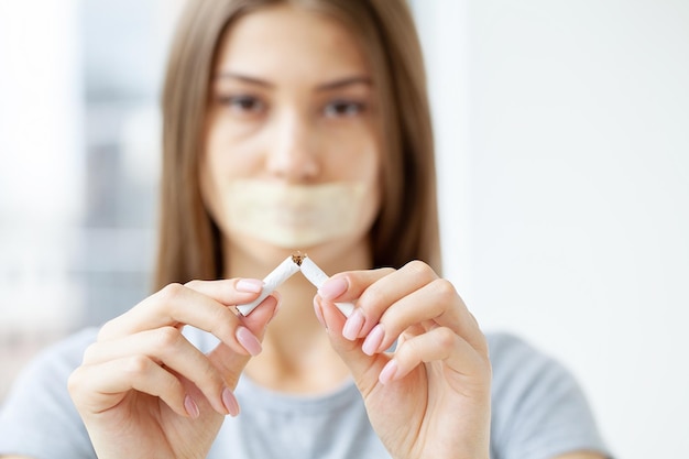 Stop smoking young woman holding a broken cigarette