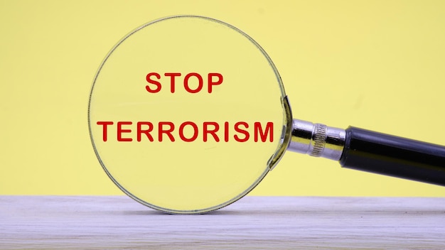 Stop Terrorism text on a yellow background through a magnifying glass