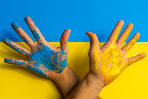 Stop war conflict between Ukraine and Russia Hands of a man painted with the colors of the Ukraine flag