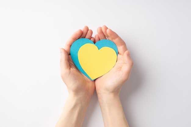 Stop the war in Ukraine concept First person top view photo of girl's hands holding yellow and blue hearts on palms on isolated white background