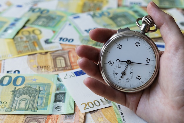 A stopwatch in a hand on one euros notes background