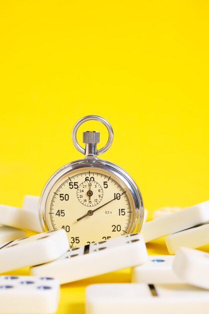 Photo stopwatch and scattered dominoes on a yellow background times up