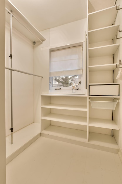 A storage room with a lot of shelves in a white design a small window in a cozy house