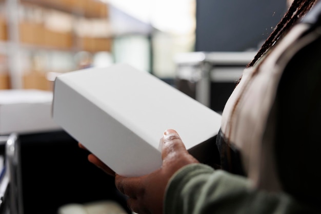 Storage room worker holding white cardboard boxes, checking products before shipping packages in warehouse. Stockroom supervisor working at customers orders during merchandise inventory