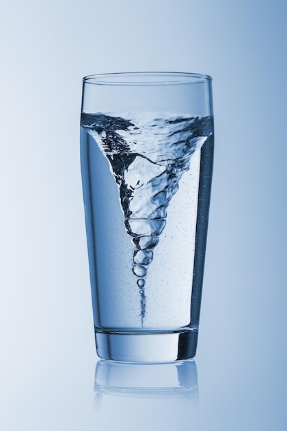 Storm tornado twister typhoon vortex in a water glass drinking on blue background