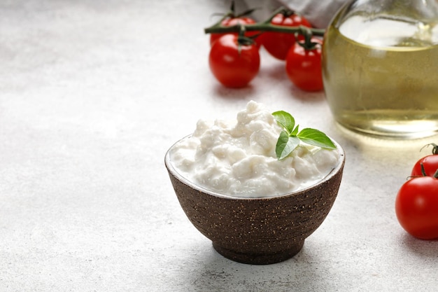 Stracciatella cheese on grey background with oil basil and tomatoes Curd cheese product