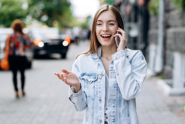 Straighthaired young beautiful smiling caucasian girl wearing casual clothes feeling happy outside Woman traveling abroad chatting on cell phone