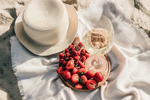 Straw beach hat with brim for sun protection with a plate of fruit and wine