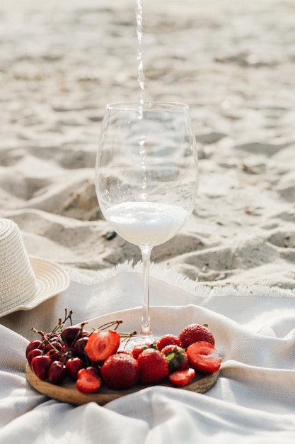 Straw beach hat with brim for sun protection with a plate of fruit and wine