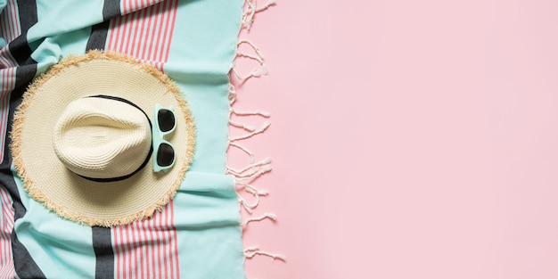 Straw beach sunhat and sun glasses on punchy pink with space for text. 