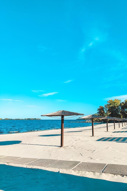 Straw beach umbrellas for shade near the river on the background of the landscape