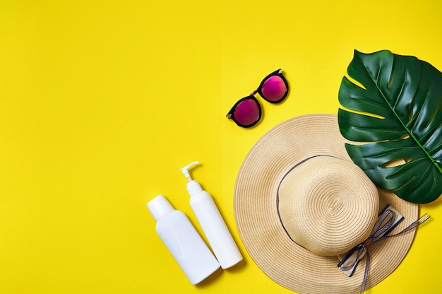 Straw hat, pink sunglasses and palm leaf on yellow background. Creative minimal concept. Top view Flat lay