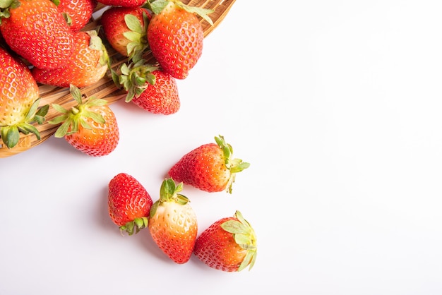 Strawberries, beautiful strawberries dropped from a straw braided basket onto a white surface, selective focus.