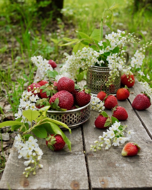 Strawberries and cherry blossom flowers on the old table