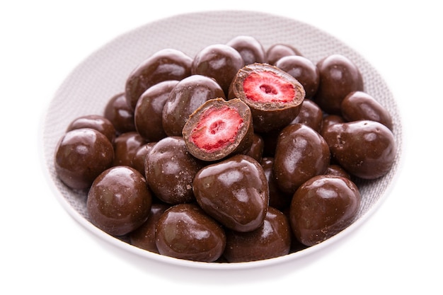 Strawberries in dark chocolatecandies in a white dish closeupisolated food products