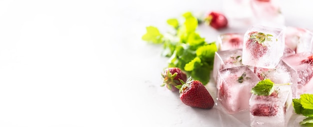 Strawberries frozen in ice cubes with melissa leaves banner with copy cpace