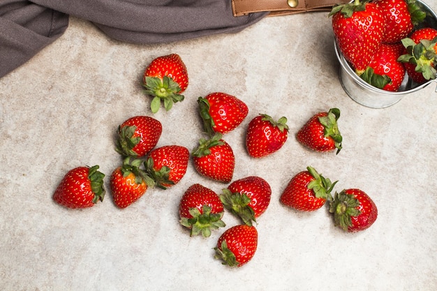 Strawberries in a galvanized bucket and on a marble table