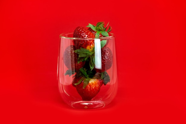 Strawberries in a glass with highlights closeup on a red background