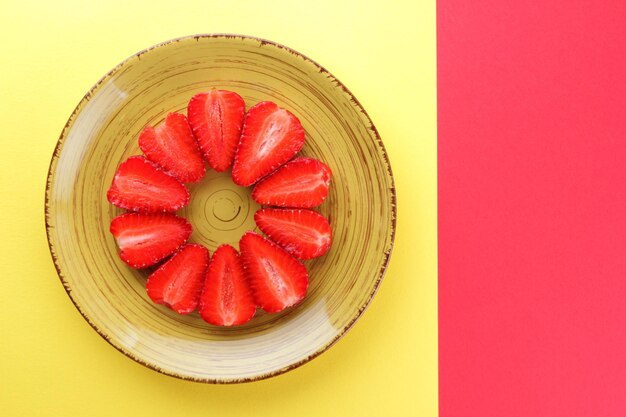 Strawberries on red background Sliced strawberries on yellow plate Vegetarian healthy food Top view Copy space