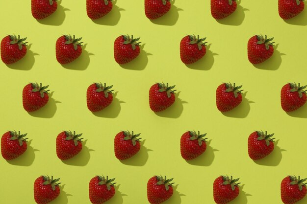 Strawberries with leaves on yellow background top view