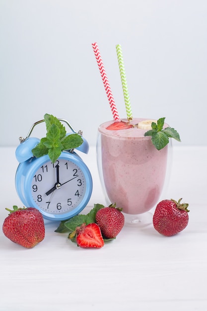 Strawberry and banana healthy smoothie with fresh strawberrys in glass decorated with mint.