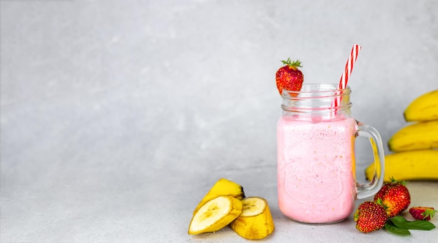 Strawberry banana milkshake in glass jars with fresh strawberries Banner with place for text