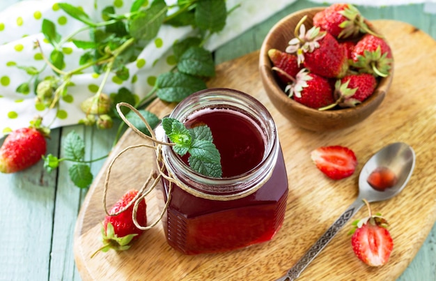 Strawberry berry syrup and fresh strawberry berries on a wooden table