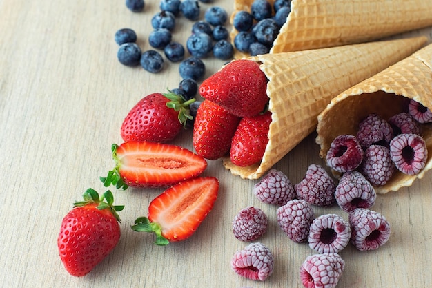 Strawberry blueberry raspberry in waffle cones on light wooden background Close Up