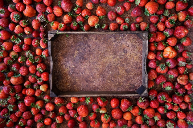 Strawberry on brown background, top view. Frame made of fresh strawberry and wooden box