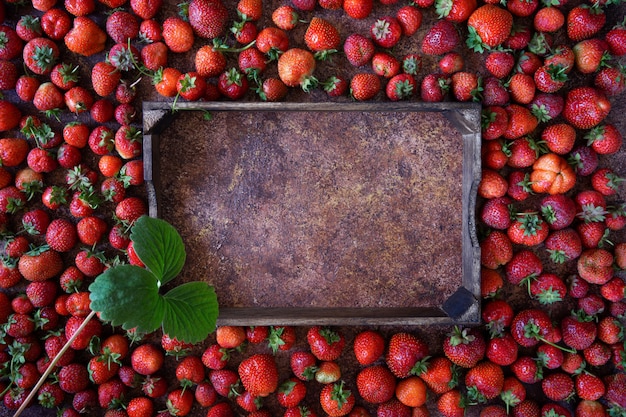 Strawberry on brown background, top view. Frame made of fresh strawberry and wooden box