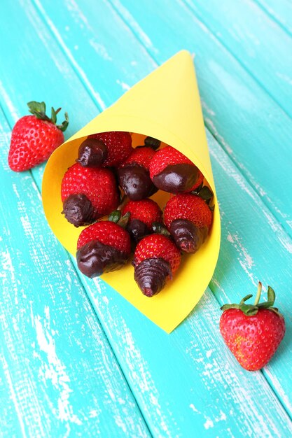 Strawberry in chocolate on skewers in paper bag on table close-up